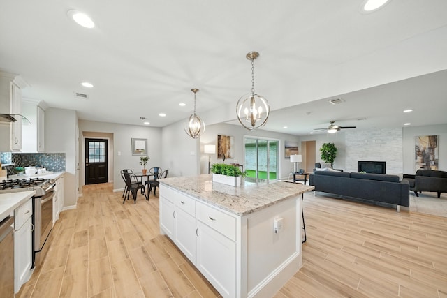 4003 Mischire Dr, Houston, TX 77025 - kitchen featuring gas stove, light wood finished floors, a kitchen island, white cabinetry, and recessed lighting
