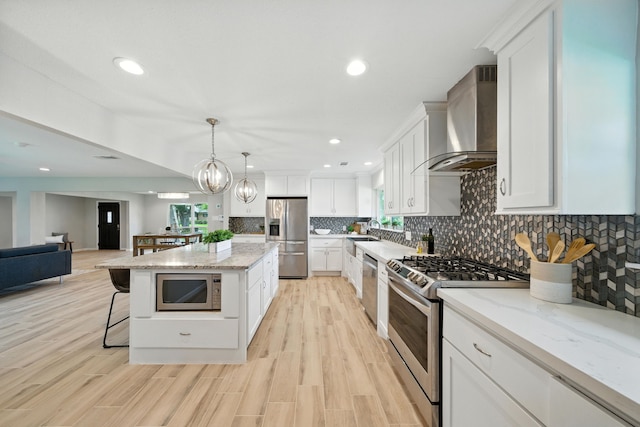 4003 Mischire Dr, Houston, TX 77025 - kitchen with stainless steel appliances, wall chimney range hood, a kitchen breakfast bar, tasteful backsplash, and white cabinetry