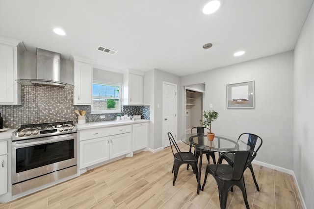 4003 Mischire Dr, Houston, TX 77025 - kitchen featuring stainless steel gas range, wall chimney exhaust hood, tasteful backsplash, light countertops, and white cabinets