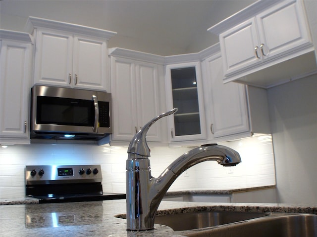 16725 Stonefield, Montgomery, TX 77316 - kitchen featuring stainless steel appliances, white cabinets, tasteful backsplash, and glass insert cabinets