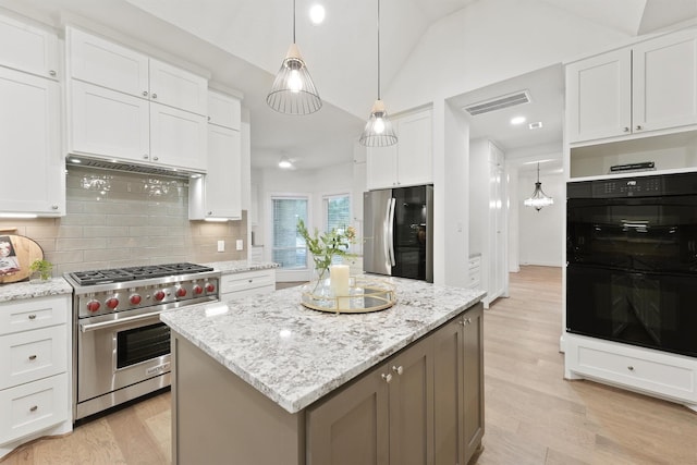 11 Forge Hill Pl, The Woodlands, TX 77381 - kitchen with stainless steel appliances, decorative backsplash, vaulted ceiling, white cabinetry, and light stone counters