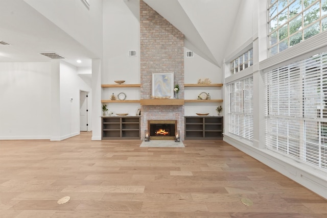 11 Forge Hill Pl, The Woodlands, TX 77381 - unfurnished living room with a brick fireplace, light wood-type flooring, and high vaulted ceiling