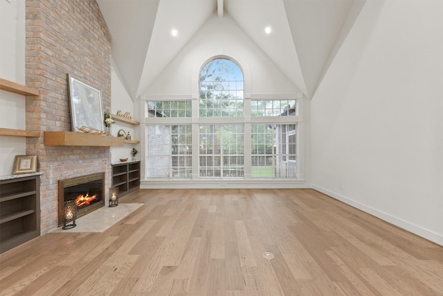 11 Forge Hill Pl, The Woodlands, TX 77381 - unfurnished living room featuring a brick fireplace, light wood-style floors, and high vaulted ceiling