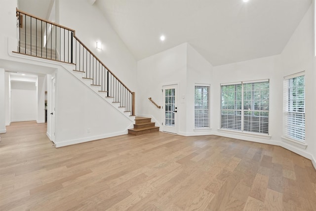11 Forge Hill Pl, The Woodlands, TX 77381 - unfurnished living room featuring high vaulted ceiling, light wood-style flooring, stairway, and recessed lighting