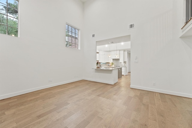 11 Forge Hill Pl, The Woodlands, TX 77381 - unfurnished living room featuring light wood-type flooring, plenty of natural light, and a high ceiling
