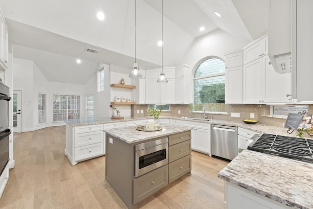 11 Forge Hill Pl, The Woodlands, TX 77381 - kitchen featuring dishwasher, high vaulted ceiling, light wood-style floors, backsplash, and white cabinets