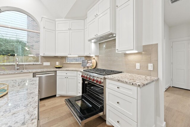 11 Forge Hill Pl, The Woodlands, TX 77381 - kitchen with appliances with stainless steel finishes, light wood finished floors, white cabinets, decorative backsplash, and lofted ceiling