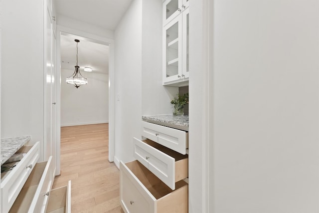11 Forge Hill Pl, The Woodlands, TX 77381 - kitchen featuring light wood finished floors, white cabinetry, glass insert cabinets, and hanging light fixtures