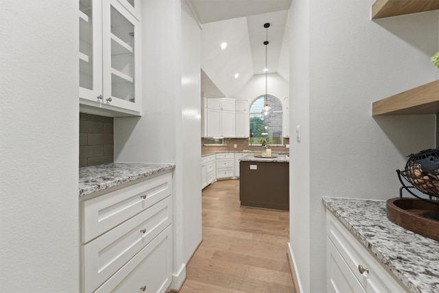 11 Forge Hill Pl, The Woodlands, TX 77381 - kitchen featuring vaulted ceiling, tasteful backsplash, white cabinets, light wood-type flooring, and glass insert cabinets