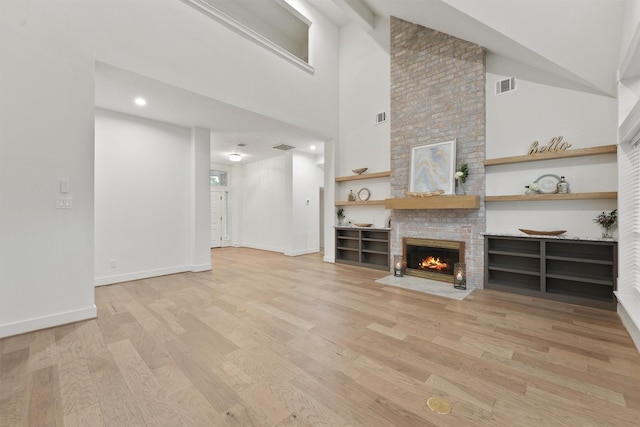 11 Forge Hill Pl, The Woodlands, TX 77381 - unfurnished living room featuring light wood-type flooring, a fireplace, built in features, high vaulted ceiling, and recessed lighting