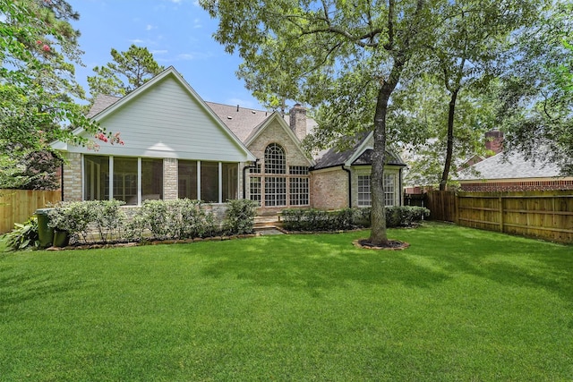 11 Forge Hill Pl, The Woodlands, TX 77381 - rear view of house with a fenced backyard, a sunroom, a chimney, and brick siding