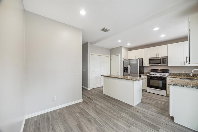 2930 Grants Lake Blvd Unit 2104, Sugar Land, TX 77479 - kitchen with stainless steel appliances, a kitchen island, dark stone counters, light wood-style flooring, and white cabinetry