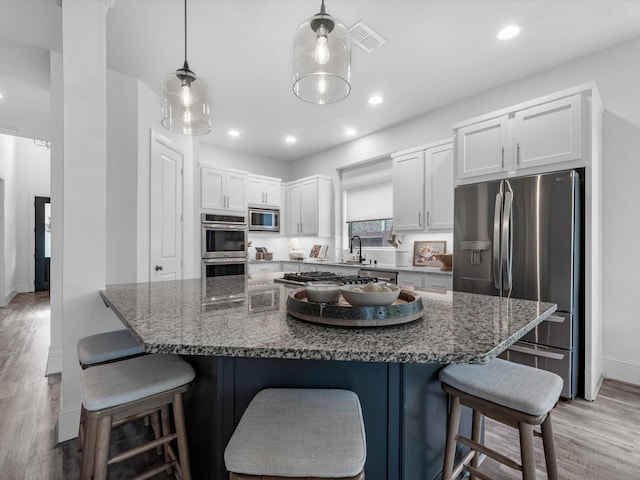 10515 Trinity Springs Dr, Cypress, TX 77433 - kitchen with stainless steel appliances, light wood-style flooring, white cabinets, recessed lighting, and a breakfast bar area