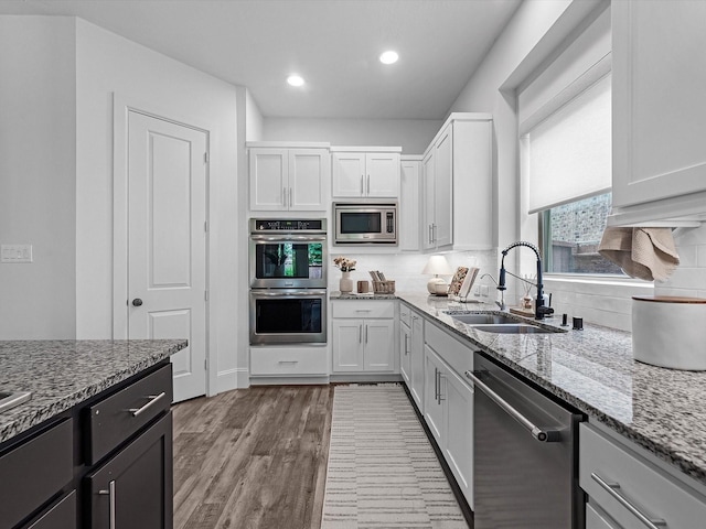 10515 Trinity Springs Dr, Cypress, TX 77433 - kitchen featuring stainless steel appliances, light stone counters, backsplash, wood finished floors, and white cabinetry