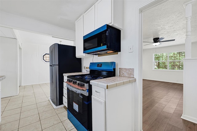 12434 Kathryn St, Houston, TX 77015 - kitchen with appliances with stainless steel finishes, tile countertops, ceiling fan, white cabinetry, and light wood-style floors