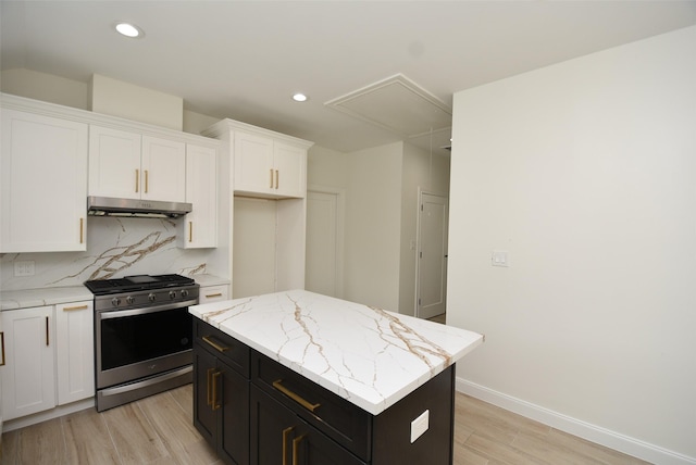729 Caperton St, Houston, TX 77022 - kitchen featuring stainless steel gas stove, under cabinet range hood, light wood-type flooring, white cabinets, and dark cabinets