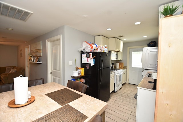 729 Caperton St, Houston, TX 77022 - kitchen featuring white gas stove, freestanding refrigerator, white cabinetry, light countertops, and stacked washing machine and dryer