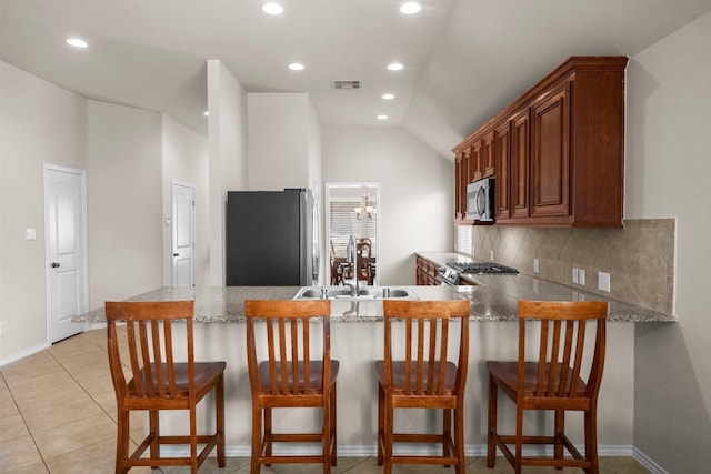 31870 Forest Park Trl, Conroe, TX 77385 - kitchen with appliances with stainless steel finishes, a peninsula, vaulted ceiling, brown cabinets, and recessed lighting
