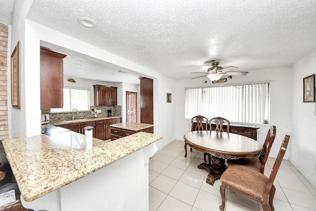 13411 Natasha Ln, Houston, TX 77015 - kitchen with ceiling fan, backsplash, a kitchen island, a textured ceiling, and a breakfast bar