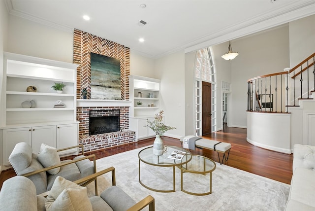 1211 Villmont Ln, Houston, TX 77077 - living room featuring ornamental molding, wood finished floors, built in features, a brick fireplace, and stairway