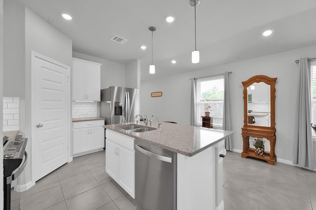18529 Meadow Point Ln, Montgomery, TX 77316 - kitchen with appliances with stainless steel finishes, tasteful backsplash, light stone countertops, an island with sink, and white cabinetry