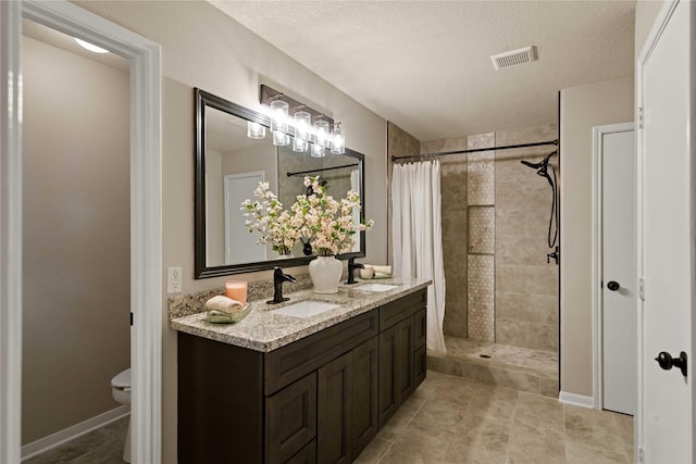12106 Hawthorne Hill Cir, Humble, TX 77346 - bathroom with tiled shower, double vanity, and a textured ceiling