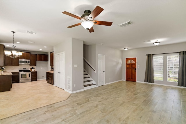 12106 Hawthorne Hill Cir, Humble, TX 77346 - unfurnished living room with stairway, a chandelier, a ceiling fan, light wood finished floors, and recessed lighting