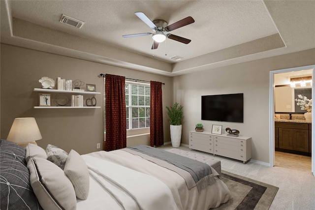 12106 Hawthorne Hill Cir, Humble, TX 77346 - bedroom featuring a tray ceiling, light colored carpet, a textured ceiling, ensuite bathroom, and ceiling fan
