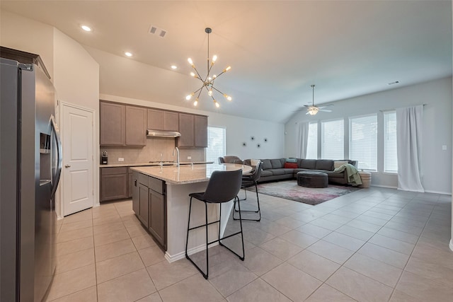 25446 Fossa Dr, Tomball, TX 77375 - kitchen featuring stainless steel fridge, light tile patterned floors, lofted ceiling, under cabinet range hood, and decorative backsplash