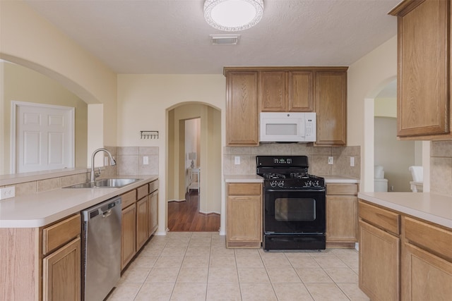 18107 Mayfield Meadow Ln, Richmond, TX 77407 - kitchen with black gas range oven, stainless steel dishwasher, white microwave, and arched walkways