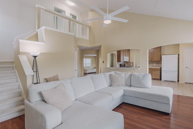 18107 Mayfield Meadow Ln, Richmond, TX 77407 - living area featuring a ceiling fan, high vaulted ceiling, stairs, arched walkways, and light wood finished floors
