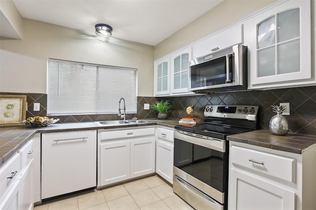 2151 Middle Creek Dr, Houston, TX 77339 - kitchen featuring stainless steel appliances, tile counters, white cabinetry, and backsplash