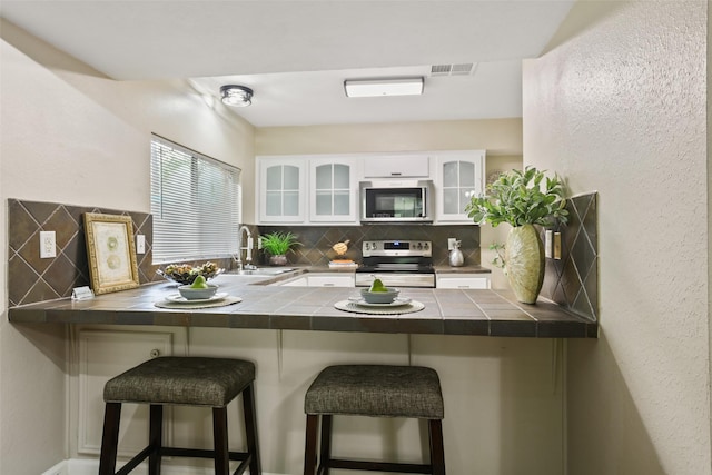 2151 Middle Creek Dr, Houston, TX 77339 - kitchen with appliances with stainless steel finishes, a peninsula, decorative backsplash, and tile countertops