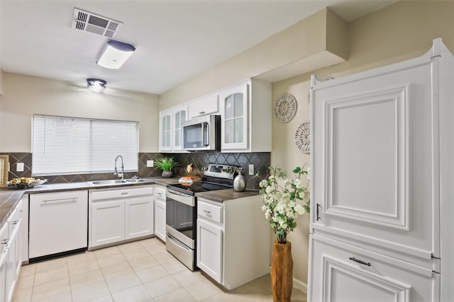 2151 Middle Creek Dr, Houston, TX 77339 - kitchen with stainless steel appliances, tasteful backsplash, dark countertops, white cabinets, and glass insert cabinets