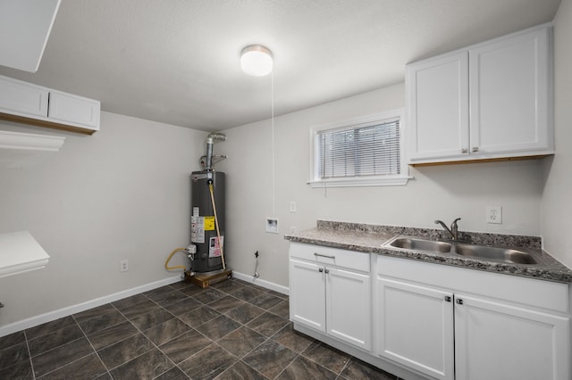 5519 Chapman St, Houston, TX 77009 - kitchen featuring water heater, white cabinetry, and dark stone finish floors
