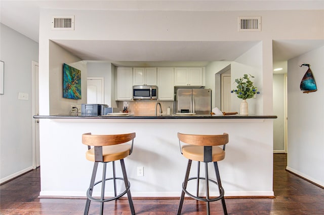 1964 Augusta Dr, Houston, TX 77057 - kitchen featuring stainless steel appliances, white cabinetry, backsplash, and a breakfast bar area