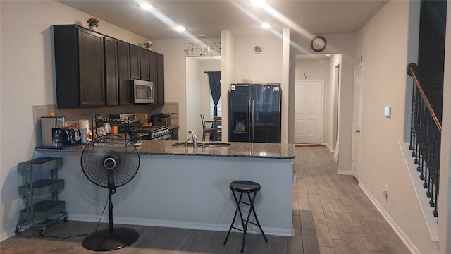 15318 Laceleaf Trl, Houston, TX 77044 - kitchen with stainless steel appliances, a peninsula, dark stone countertops, and wood finished floors