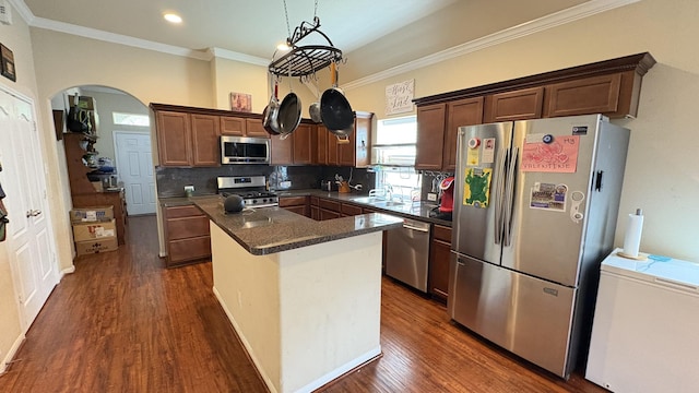 20530 Keegans Ledge Ln, Cypress, TX 77433 - kitchen with appliances with stainless steel finishes, a kitchen island, tasteful backsplash, ornamental molding, and dark wood-style flooring