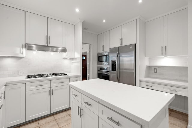 2409 Dryden Rd, Houston, TX 77030 - kitchen with stainless steel appliances, under cabinet range hood, backsplash, light tile patterned floors, and white cabinetry