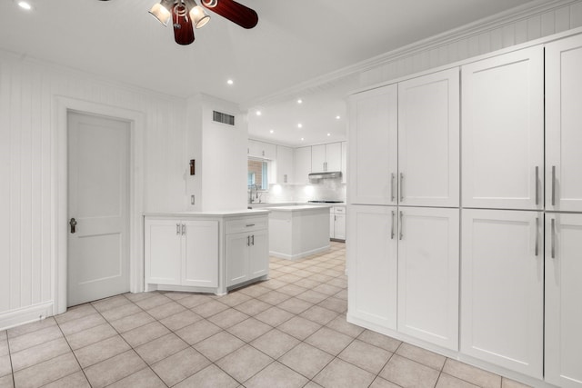 2409 Dryden Rd, Houston, TX 77030 - kitchen with a ceiling fan, white cabinetry, under cabinet range hood, ornamental molding, and light countertops