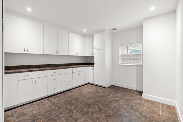 2409 Dryden Rd, Houston, TX 77030 - kitchen featuring dark countertops, white cabinetry, and recessed lighting