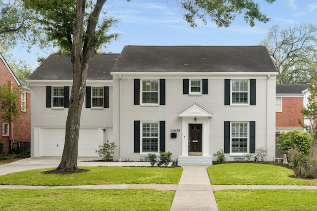 2409 Dryden Rd, Houston, TX 77030 - colonial home featuring brick siding, an attached garage, driveway, a front lawn, and roof with shingles
