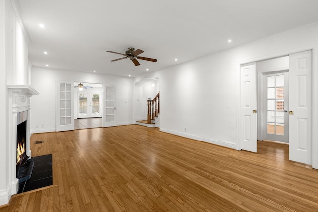 2409 Dryden Rd, Houston, TX 77030 - unfurnished living room featuring a ceiling fan, light wood-type flooring, a lit fireplace, recessed lighting, and french doors