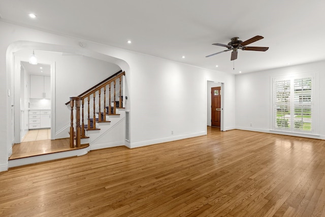 2409 Dryden Rd, Houston, TX 77030 - unfurnished living room with a ceiling fan, stairway, light wood-style floors, arched walkways, and recessed lighting
