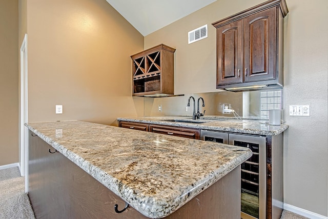 2315 Huldy St, Houston, TX 77019 - kitchen with beverage cooler, vaulted ceiling, light stone counters, dark brown cabinetry, and a peninsula