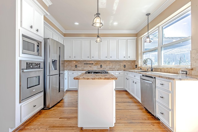 2315 Huldy St, Houston, TX 77019 - kitchen featuring appliances with stainless steel finishes, a kitchen island, ornamental molding, white cabinetry, and backsplash