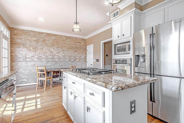 2315 Huldy St, Houston, TX 77019 - kitchen featuring appliances with stainless steel finishes, white cabinetry, a kitchen island, crown molding, and light stone counters