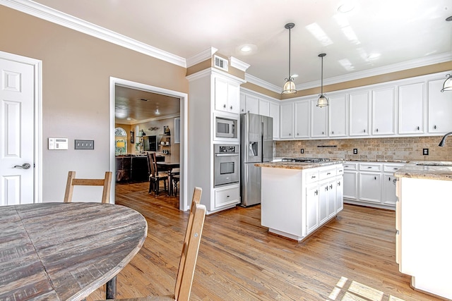 2315 Huldy St, Houston, TX 77019 - kitchen featuring stainless steel appliances, a kitchen island, white cabinets, crown molding, and backsplash