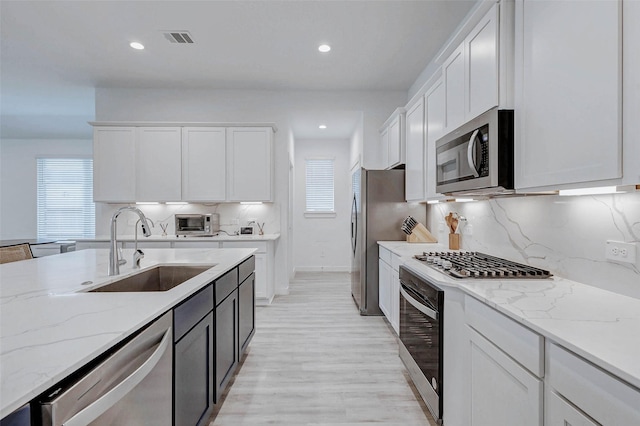 3368 Voda Bend Dr, Katy, TX 77493 - kitchen with appliances with stainless steel finishes, white cabinets, light stone countertops, backsplash, and recessed lighting
