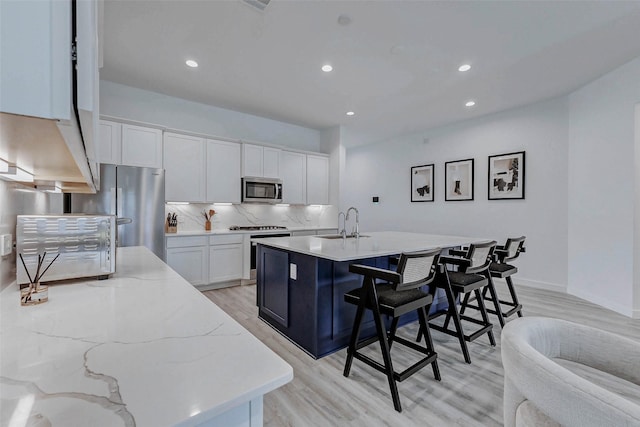 3368 Voda Bend Dr, Katy, TX 77493 - kitchen with appliances with stainless steel finishes, light wood finished floors, backsplash, white cabinets, and recessed lighting